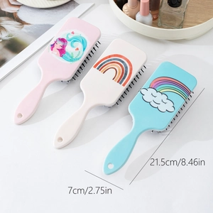 Three cute cartoon hairbrushes with mermaid and rainbow prints on a white tabletop