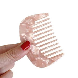 Pettine a denti larghi in acetato rosa marmorizzato per capelli da donna su sfondo bianco