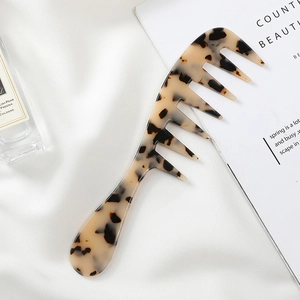 Tortoiseshell acetate wide-tooth comb displayed on white silk with elegant accessories