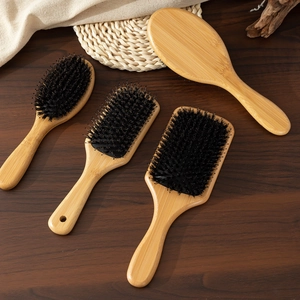 Natural bamboo paddle hair brush set with boar bristles for scalp massage on wooden desk