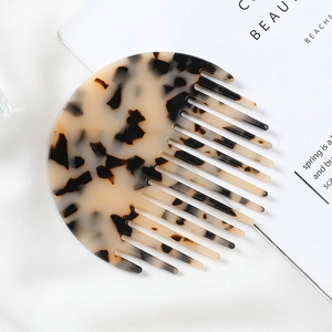 Detailed close-up of marble pattern acetate hair comb on soft white fabric background