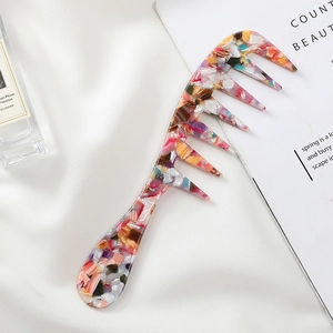 Portable wide-tooth acetate hair comb with multicolor marble texture on white satin background