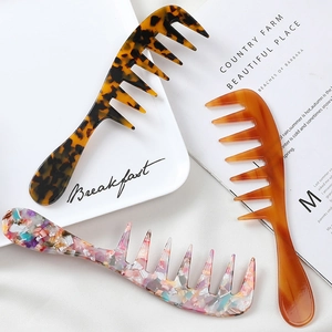 Portable acetate wide-tooth hair combs in tortoiseshell and marble patterns on a white plate