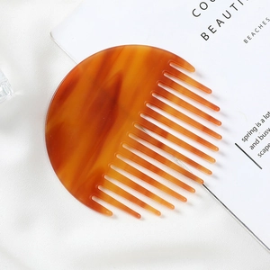 Close-up of a semi-circular acetate wide-tooth hair comb with amber tortoiseshell pattern
