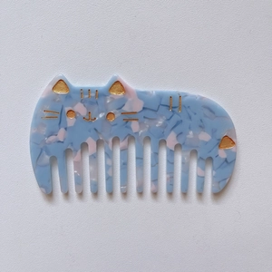 Detail of cute cat shaped acetate hair comb with blue pink marble texture and gold glitter
