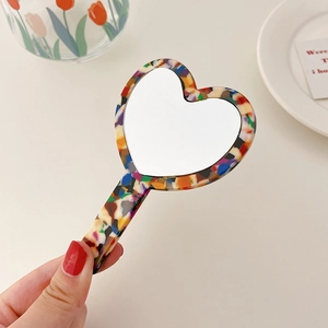 Detail view of heart-shaped tortoiseshell acetate hand mirror in an elegant setting
