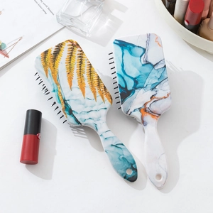 Detail view of two paddle hairbrushes with marble and golden leaf texture patterns