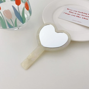Elegant heart-shaped acetate hand mirror with a creamy yellow marbled finish and long handle