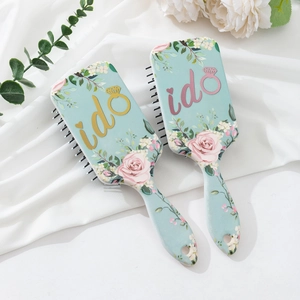 Detail of floral air cushion hairbrushes with I Do text on elegant white satin