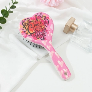 Brosse à cheveux rose en forme de cœur sur un fond de tissu en soie blanche