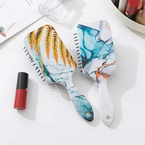 Rectangle paddle brushes with marble and floral patterns on a white cosmetic table