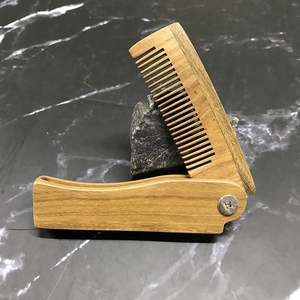 Detail of a natural sandalwood folding comb showing the silver metal pivot screw