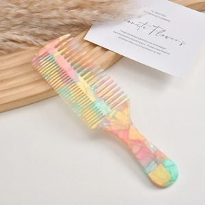 Detail of colorful acetate comb with dual teeth on a wooden tray with dried flowers