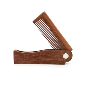 Detail of folding green sandalwood comb showing natural grain and silver metal hinge