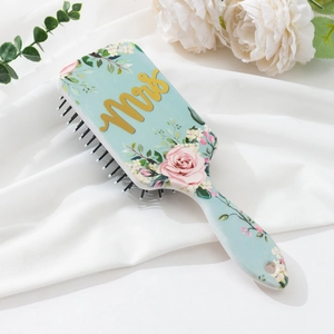 Detail of floral air cushion hairbrush with gold Mrs lettering on soft white fabric