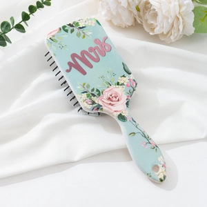 Macro view of blue floral air cushion hairbrush with pink Mrs text on white fabric