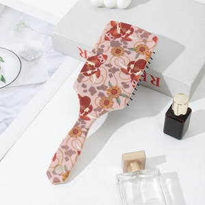 Détail de brosse plate rose avec imprimé vache écossaise et picots de massage arrondis