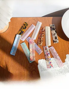 Flat acetate hair combs in various leopard and marble patterns on a wooden surface