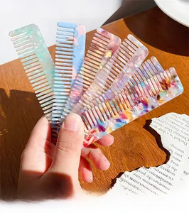 Close-up of leopard print acetate wide-tooth combs held by hand on wooden background