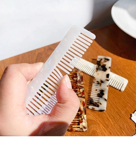 Close-up of pearl white wide-tooth acetate hair comb with marble patterns