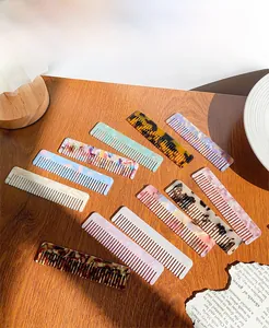 Collection of colorful leopard and marble print acetate hair combs on a wooden surface
