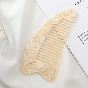 Detailed macro view of heart-shaped marble acetate wide-tooth hair comb on satin