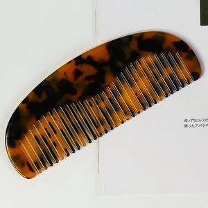 Macro shot of tortoiseshell pattern acetate hair comb with smooth rounded teeth and curved design