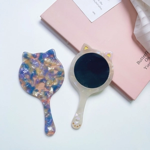 Detail view of cat-shaped acetate handheld mirrors with shell pattern and heart cutout