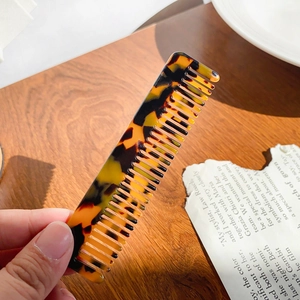 Retro leopard print acetate comb with fine teeth shown on a vintage newspaper
