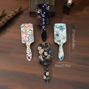 Detail view of four patterned air cushion hairbrushes with retro floral designs and dimensions