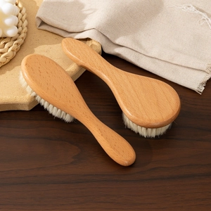 Natural beech wood baby hair brush set with soft wool bristles on a rustic wooden table
