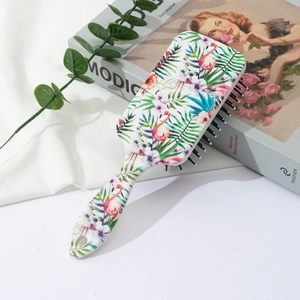Detail of tropical flamingo print on a white air cushion paddle hairbrush with black bristles