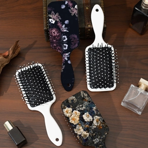 Set of four cushion hair brushes with vintage floral prints on a rustic wooden table