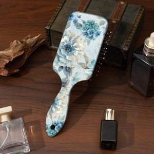 Detail of air cushion hairbrush featuring blue floral print on wooden background