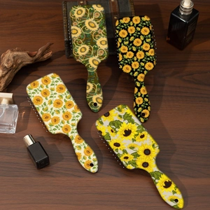 Close-up of four artistic sunflower pattern paddle hair brushes on a vintage wooden surface
