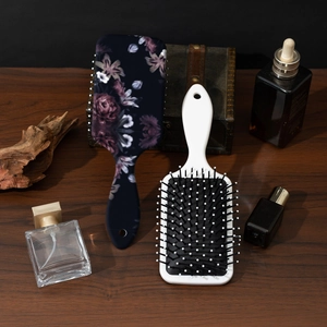 Retro floral print cushion hairbrush set with scalp massage bristles on dark wood surface