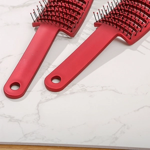 Detail of red hollow vented hair brushes with massage bristles on marble surface