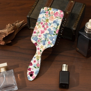 Detailed view of floral paddle brush leaning against vintage wood in warm natural lighting