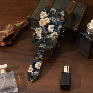 Vintage hair brush with white floral print on dark wood vanity background