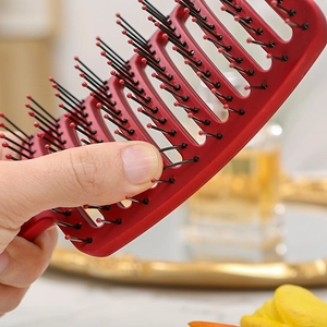 Close-up of ergonomic red vent brush with black massage bristles and hollow back design