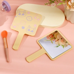 Detail of cute cat pattern print on the back of a creamy yellow handheld makeup mirror