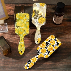 Detailed view of yellow floral patterned hair brushes on vintage wooden desk surface