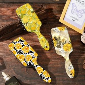 Set of three vintage yellow rose paddle hairbrushes on a rustic wooden background