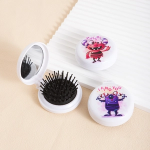 Detail of portable folding hairbrush with mirror featuring cartoon monster illustrations