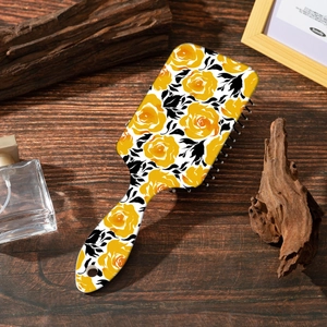 Macro detail of rectangle hairbrush back with yellow rose floral print on wooden desk