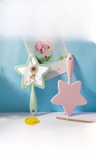 Detail of star-shaped handheld makeup mirrors in mint and pink with round hanging holes