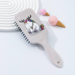 Detail of grey massage hairbrush with cute cartoon unicorn pattern on a white display