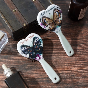 Retro heart-shaped cushion hairbrush with butterfly print on vintage wood table
