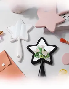 Star-shaped handheld mirrors in white, pink, and black colors on a vanity table setting