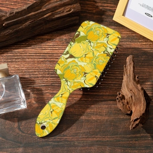 Detailed close-up of a vintage square air cushion hairbrush with yellow rose floral print